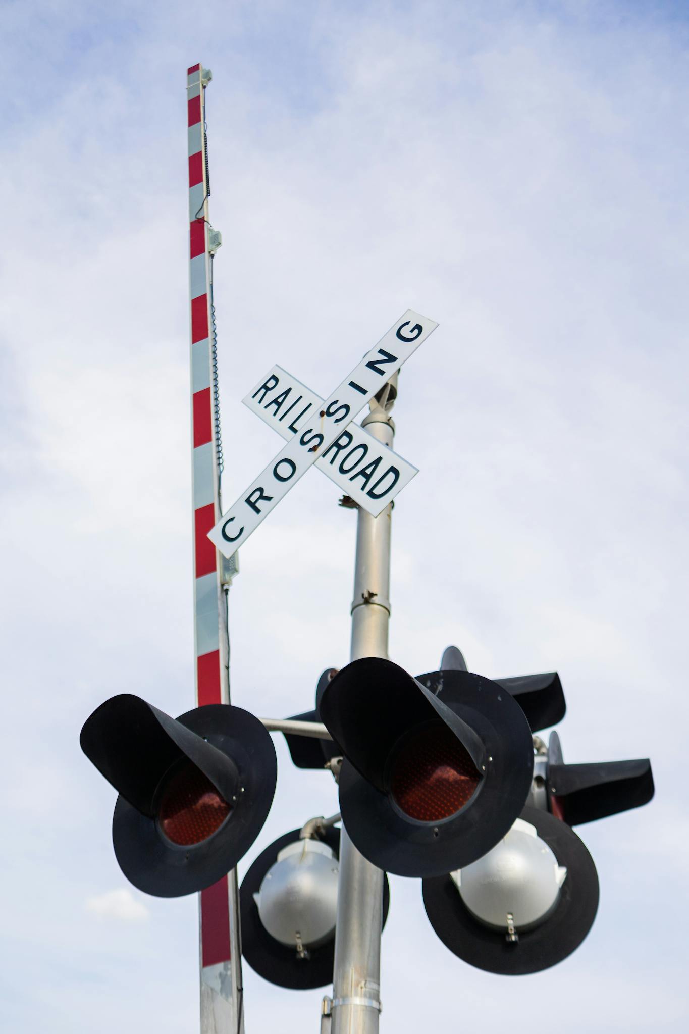 Low angle shot of a railroad crossing signal with traffic lights against a clear blue sky.