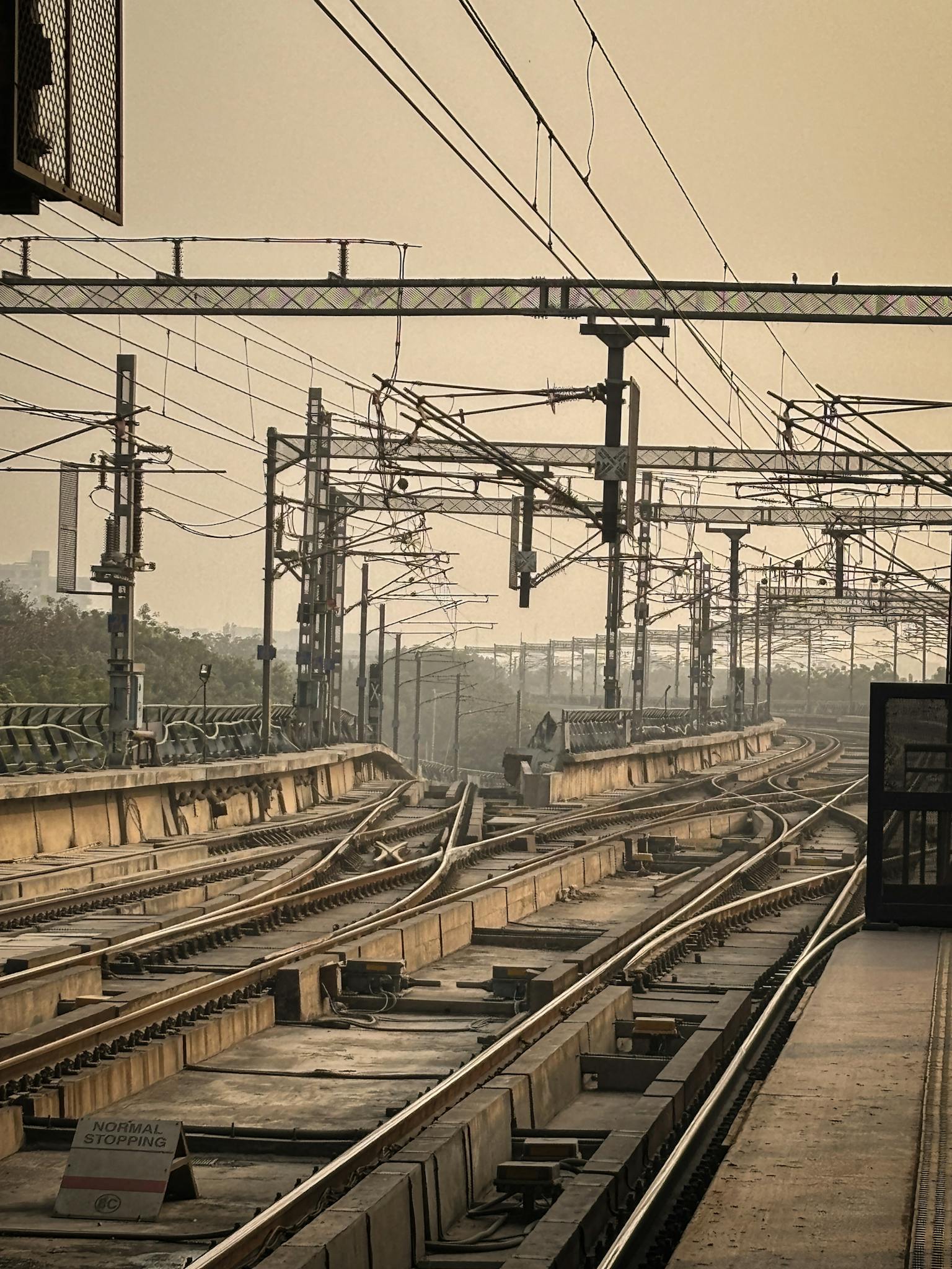Railway tracks and overhead lines in a city on a foggy day. Urban infrastructure scene.